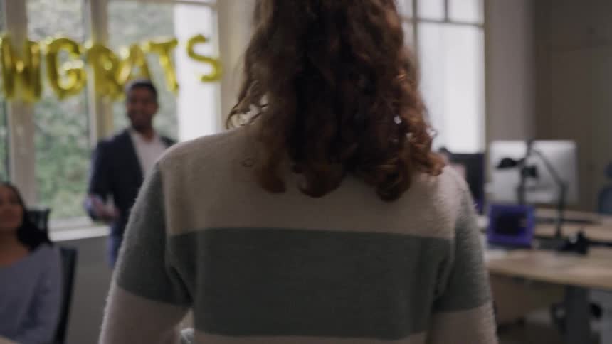 Manager congratulates a female worker while her coworker claps during a day in the office