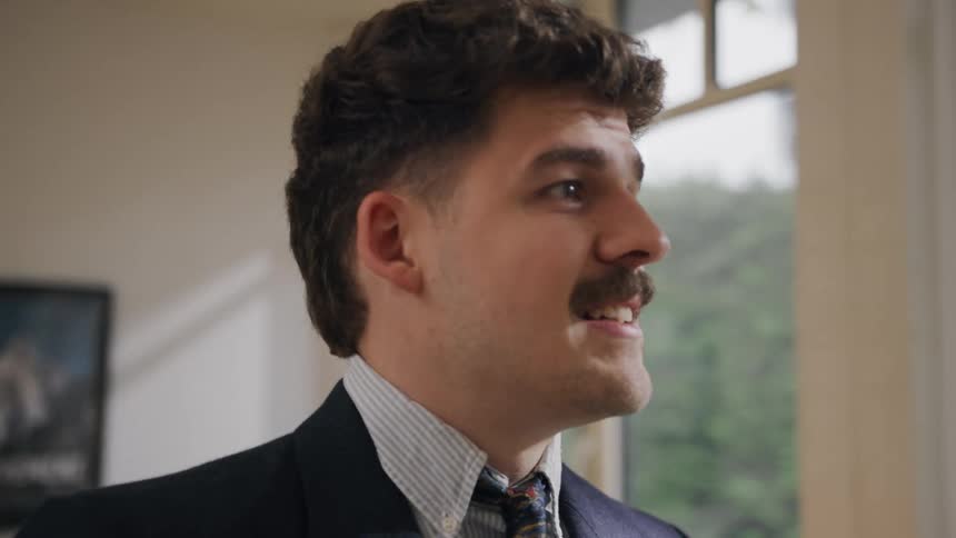 Close up of a young male office worker smiling and conversing while standing in an office during daytime