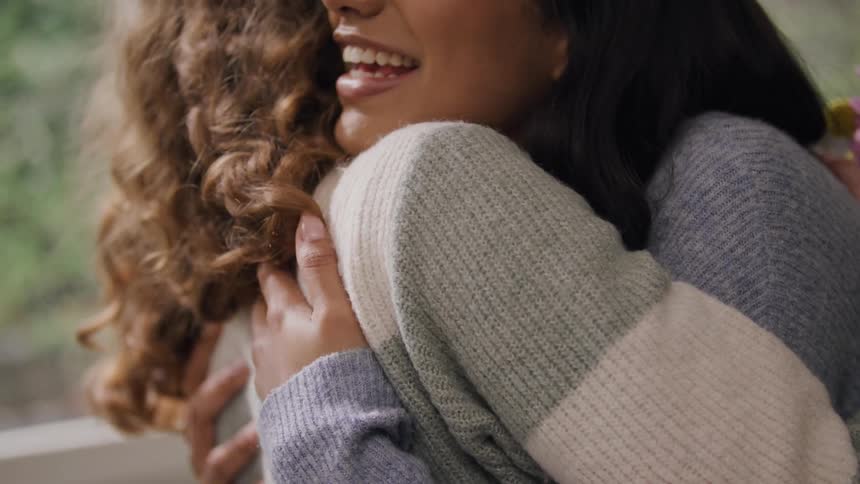 A woman hugs her friend while having a big smile