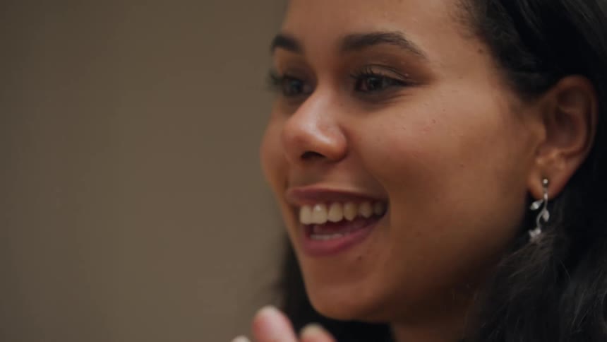 A young woman smiles and laughs during a fun discussion with another person