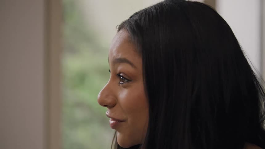 A woman smiles warmly while engaged in a conversation near a window