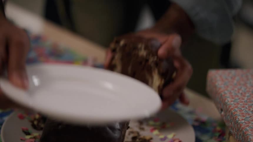 Person cutting a slice of cake and next to it a happy man