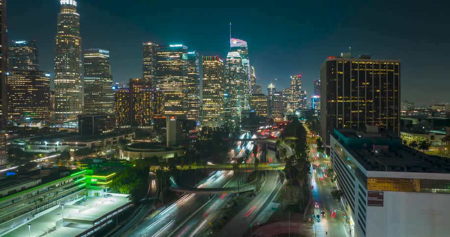 Bustling Los Angeles skyline at night with lit skyscrapers and streaking car lights