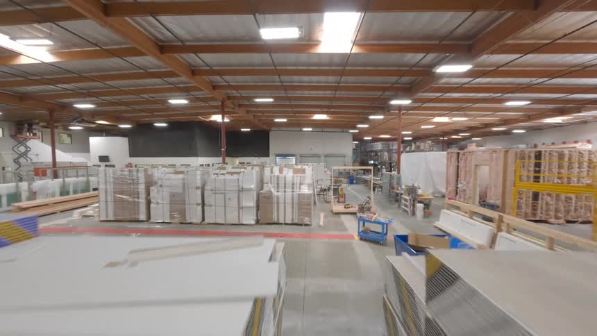 FPV drone flys around employees as they are working together in the warehouse