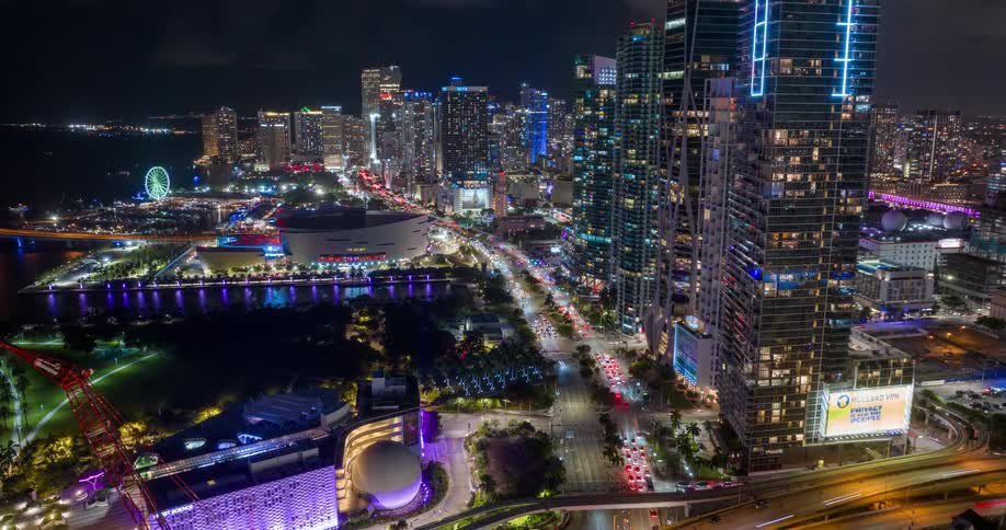 Vibrant aerial night view of a litup Miami with skyscrapers and glowing waterfront