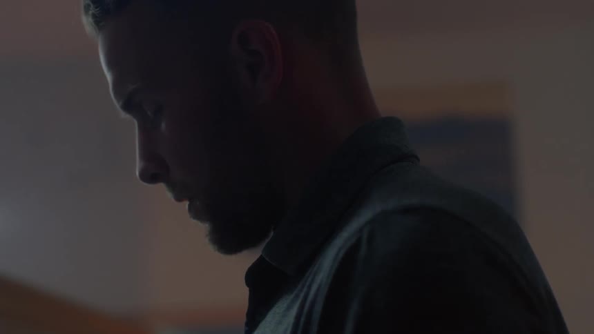 Man with closed eyes stands in a dim room