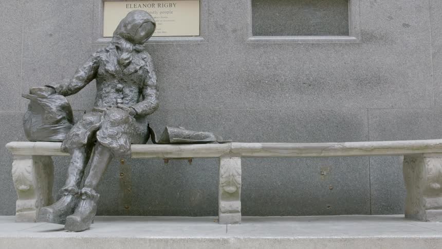A statue sitting on a bench next to a building