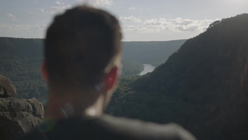 A man looks over the view from a cliff