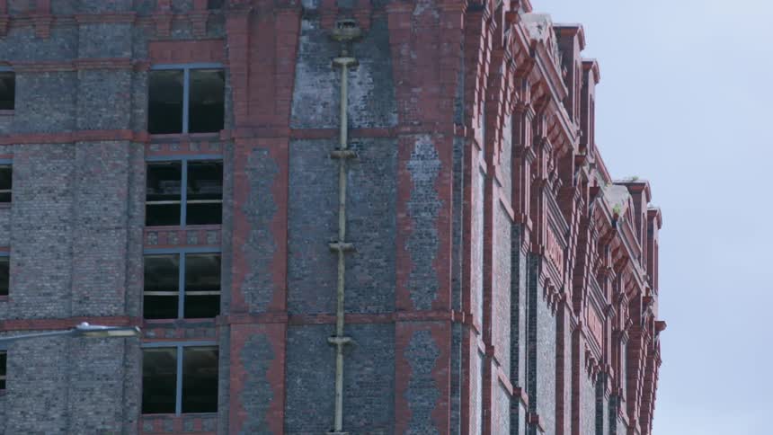 A tall stone building with windows stands against a blue sky