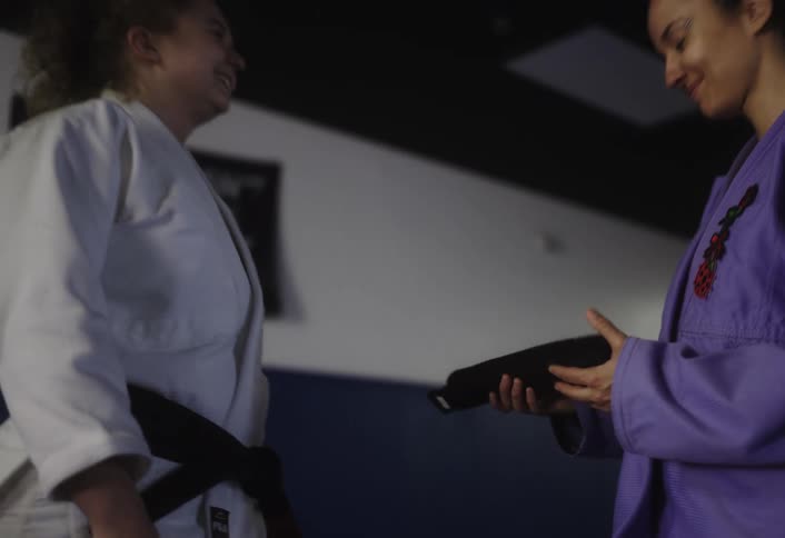 A woman is given a black belt in the gym