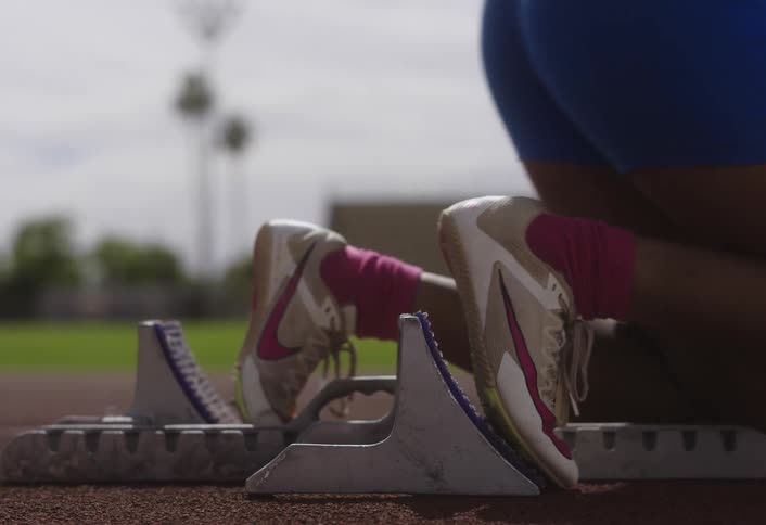A sprinter prepares to launch from starting blocks on a track