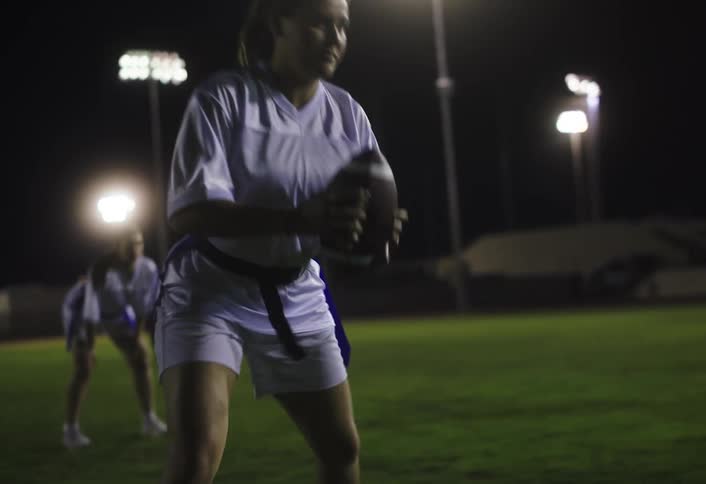 A woman runs with the football at night