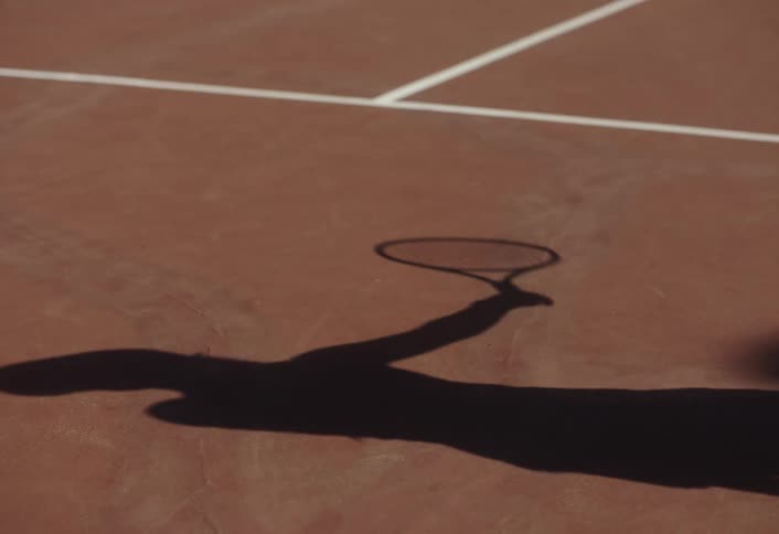The shadow of a female playing a game of tennis outdoors