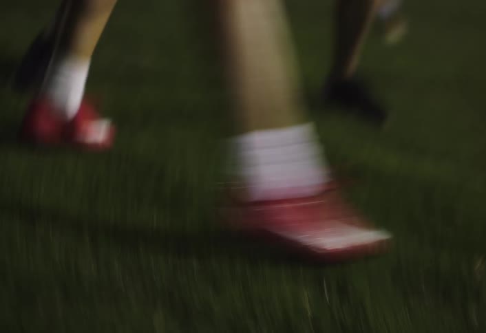 Person with red cleats running on artificial grass and playing soccer