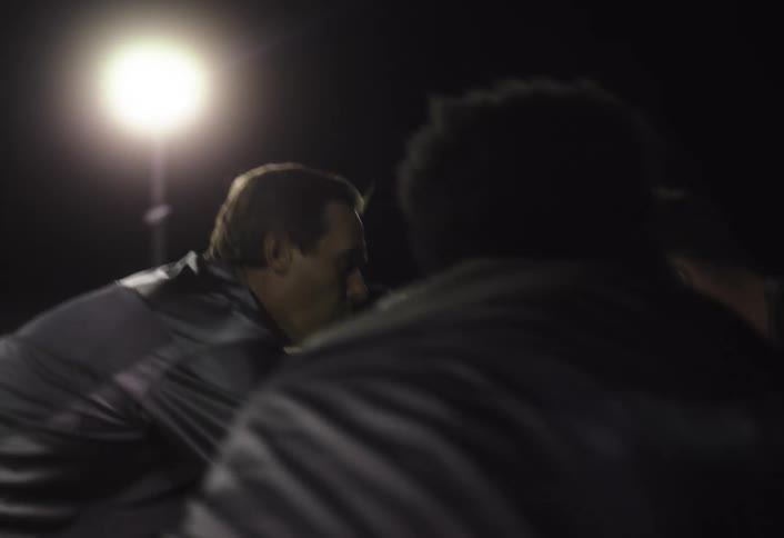 Football players on the field cheer each other on during a nighttime match
