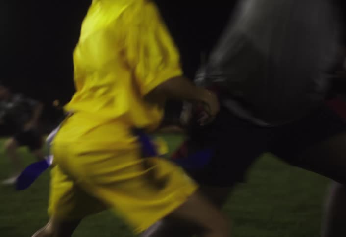 Football players charge on the field at night