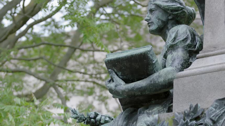 Trees sway behind a statue