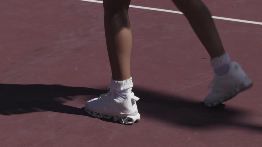 Close up of a females legs as she plays tennis on court outdoors during daytime