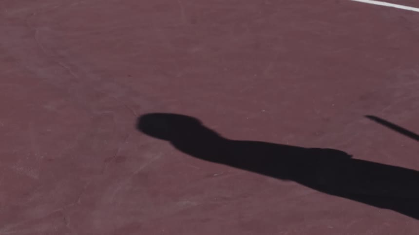 Shadow of someone playing tennis on the tennis court on a sunny day