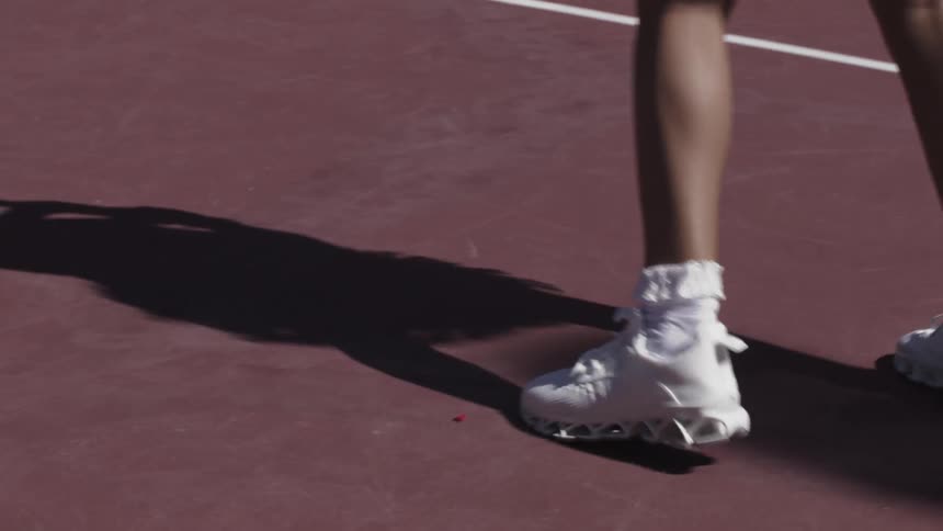 Legs and shadows of a woman on a tennis court