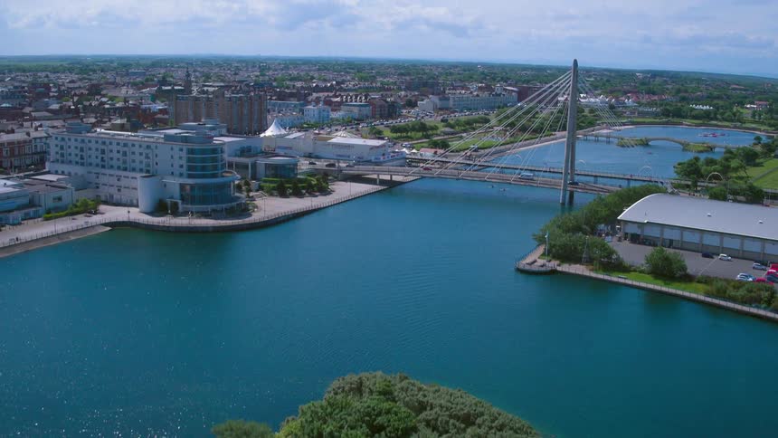 Boats sail along a waterway toward a bridge in a small city