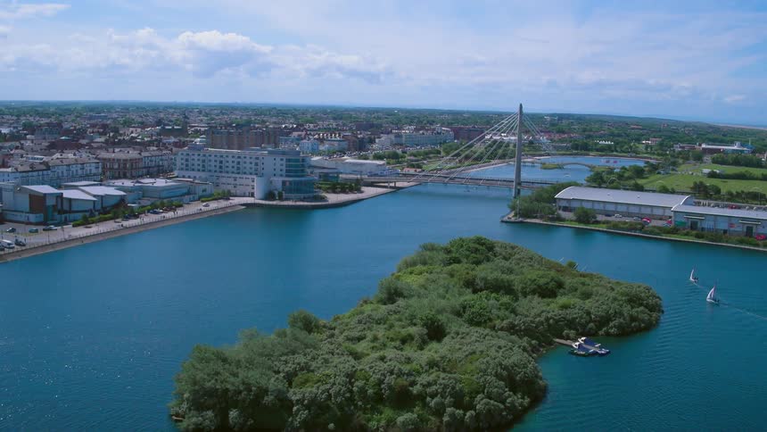 A sailboat floats in a waterbody next to a city