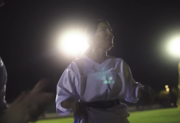 A group of rugby players huddle on nighttime turf firing each other up with animated gestures and intense focus