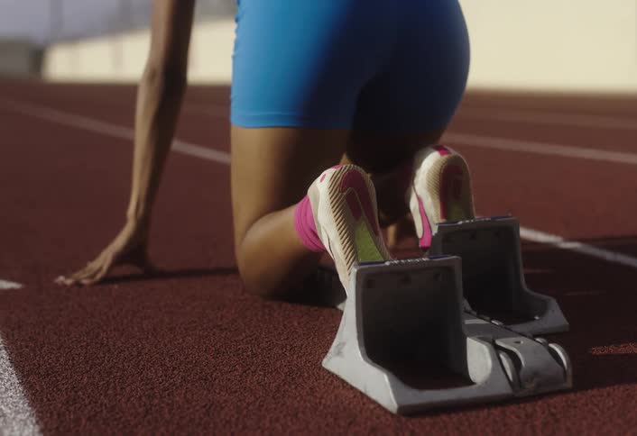 Woman positioning herself in a longdistance race on an athletics track and running at high intensity