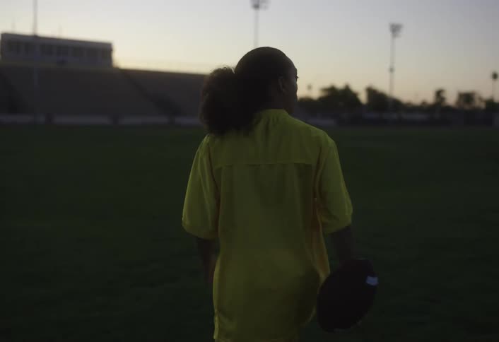 A woman carries the football over the field
