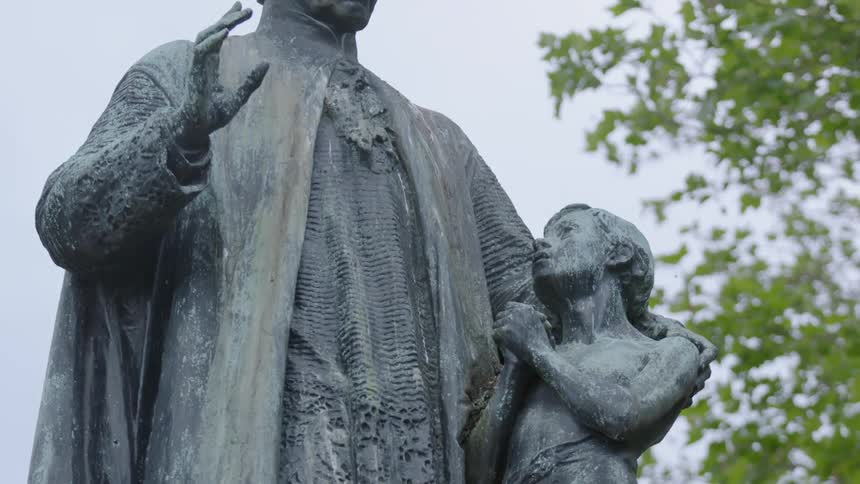 A statue is near a tree on a cloudy day