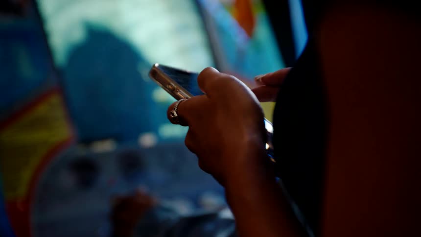 An arcade center features a man playing an arcade game while a woman beside him scrolls through her phone