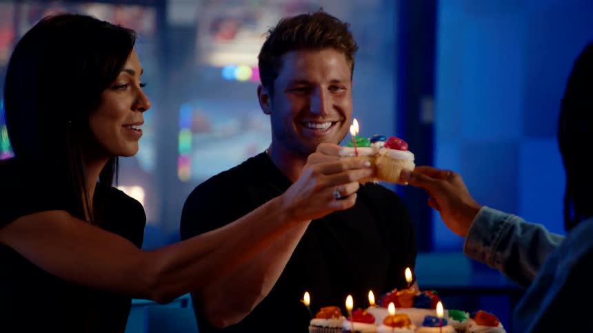 Friends celebrate with cupcakes and candles in a warmly lit birthday gathering