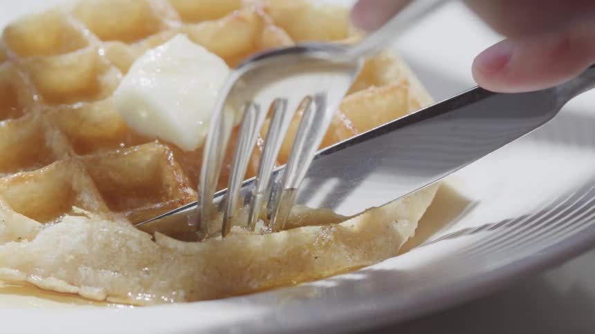 Cutting a waffle with a fork and knife