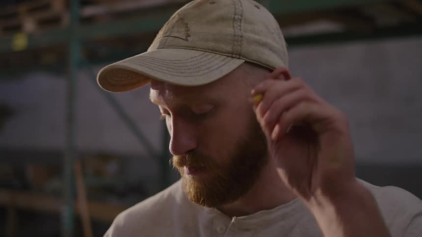 The man grabs a pencil from his ear