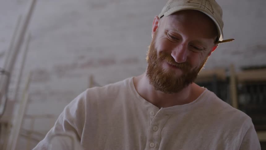 The carpenter smiles while he uses a saw