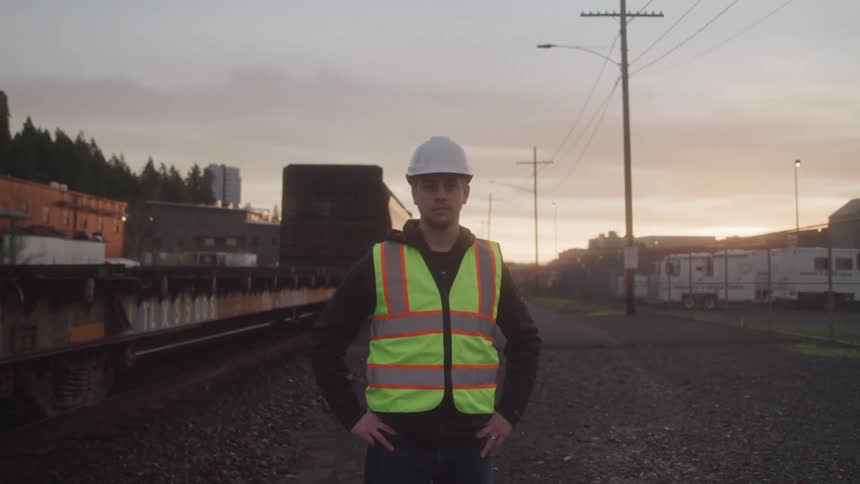 A worker stands near a moving train
