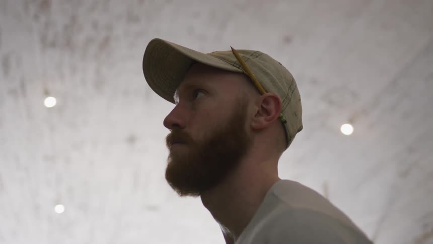 Man wearing a baseball cap looks around a well lit room
