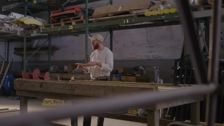 A man works alone at a large workbench in a spacious industrial workshop