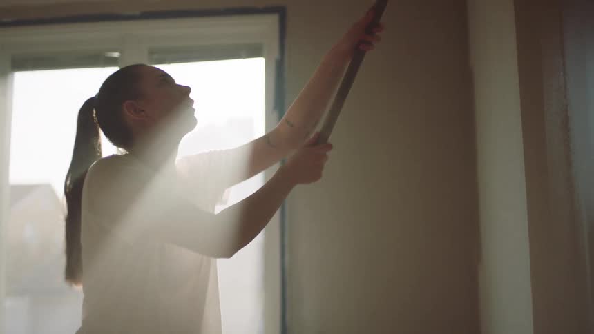 Woman is painting the walls a different color inside her home