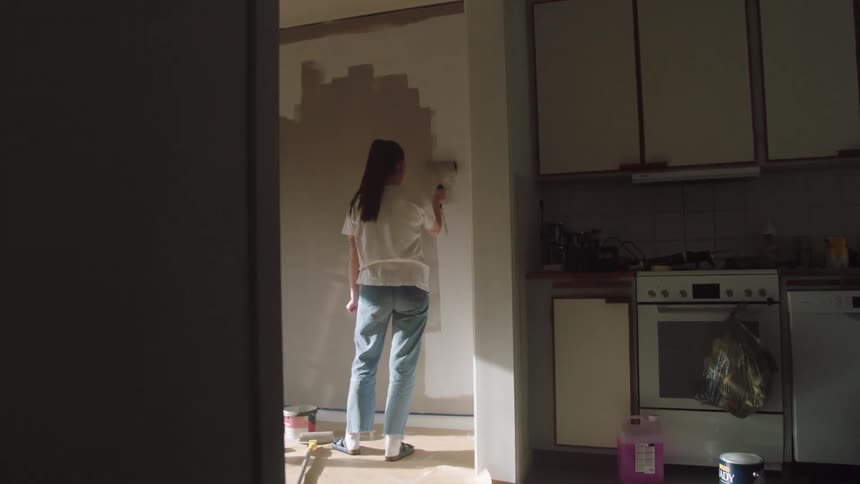 A woman paints a wall
