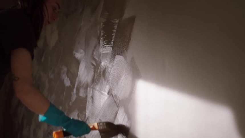 A woman uses a brush to paint the wall