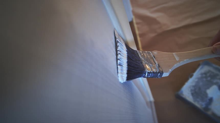 Point of view painting an interior wall with downward brush strokes