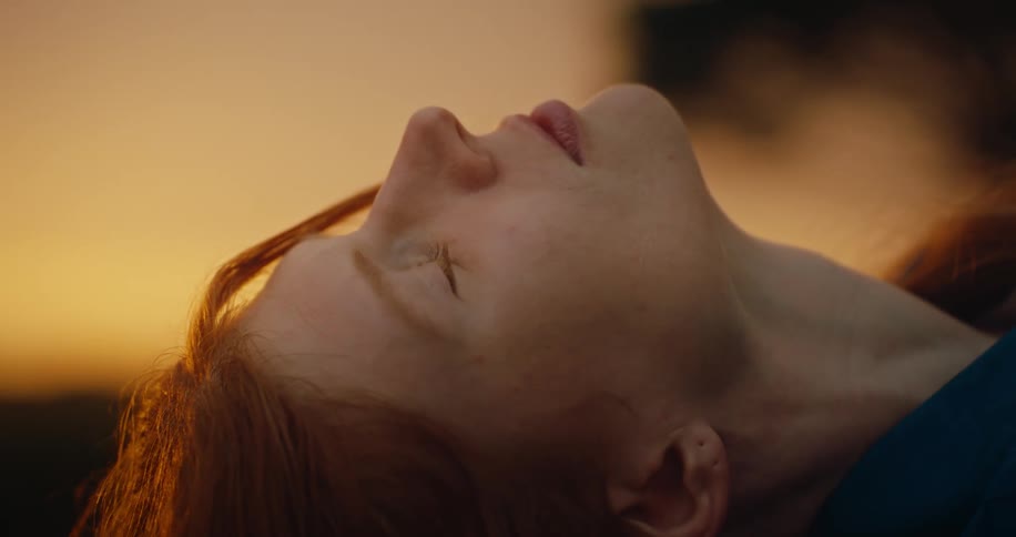 Woman is laying on the outdoors ground while the sun sets