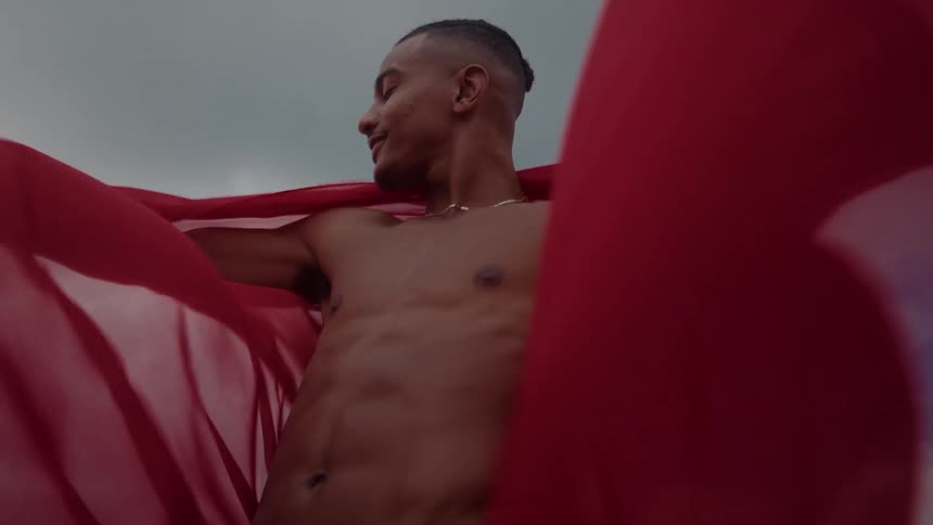 A man is holding flowing red sheets