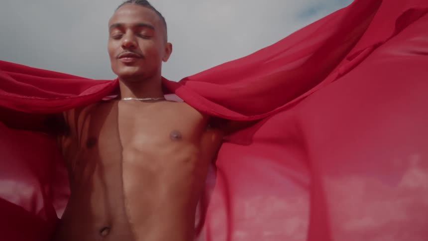 A man stands with a red cape billowing behind him