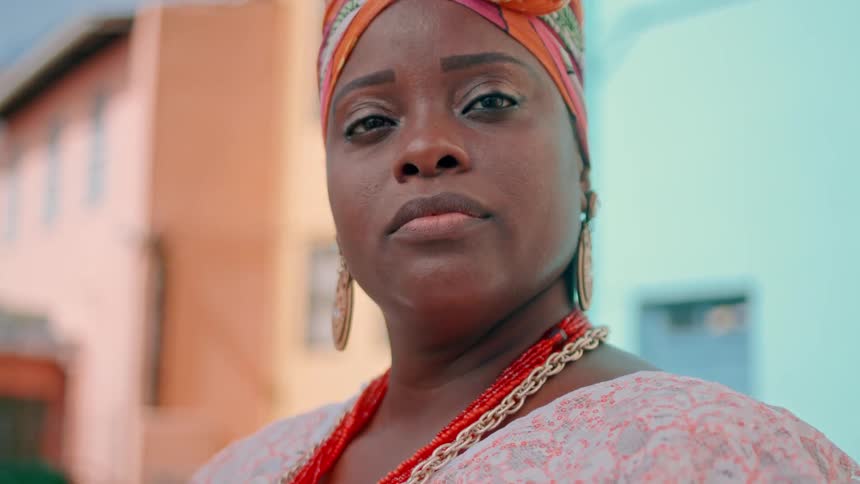 A confident woman in traditional attire looks directly at the camera