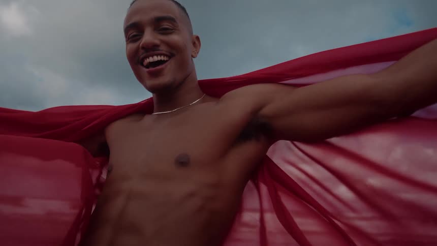 A man stands with red fabric draped around him