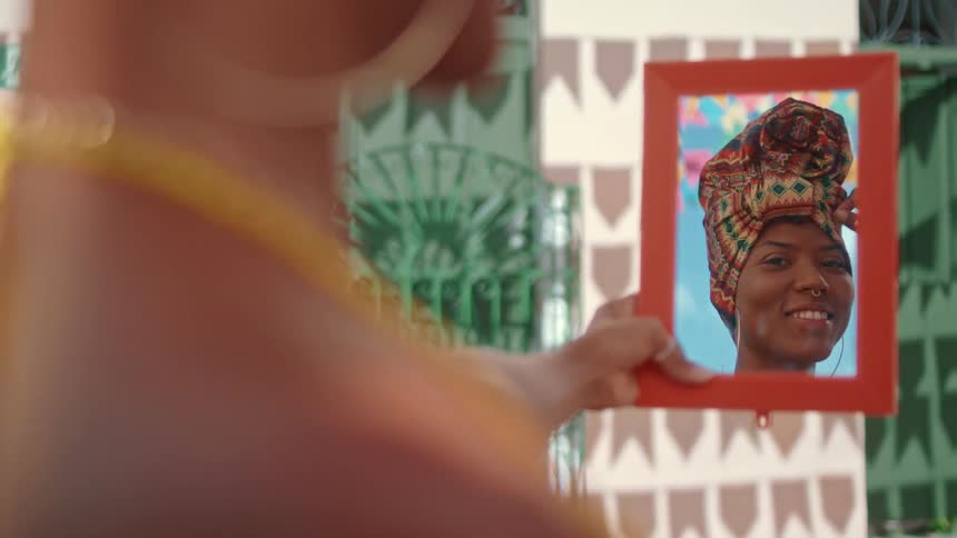 A woman adjusts her turban in the mirror