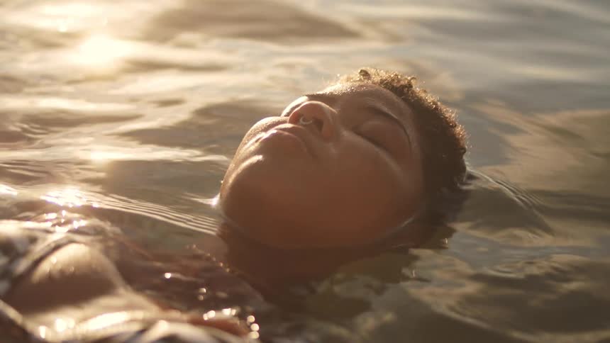 A woman is floating on a body of water on a sunny day