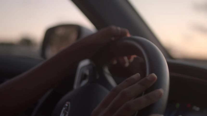 A woman is tapping on her steering wheel